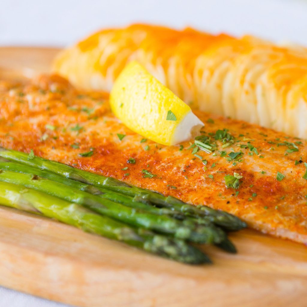 A plate of fish, potatoes and asparagus with a lemon wedge at 1852 Grill Room restaurant on Mackinac Island
