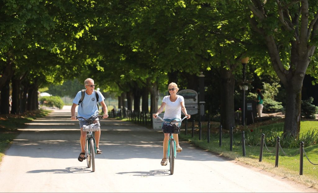 Two people ride bicycles down a Mackinac Island street on a sunny summer day