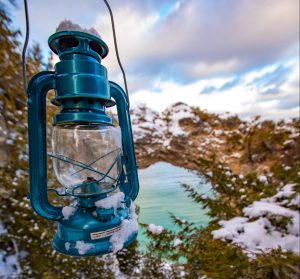 A lantern is held in front of Mackinac Island's Arch Rock on a snowy winter day