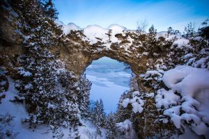 Snow covers Mackinac Island's iconic Arch Rock on a clear winter day
