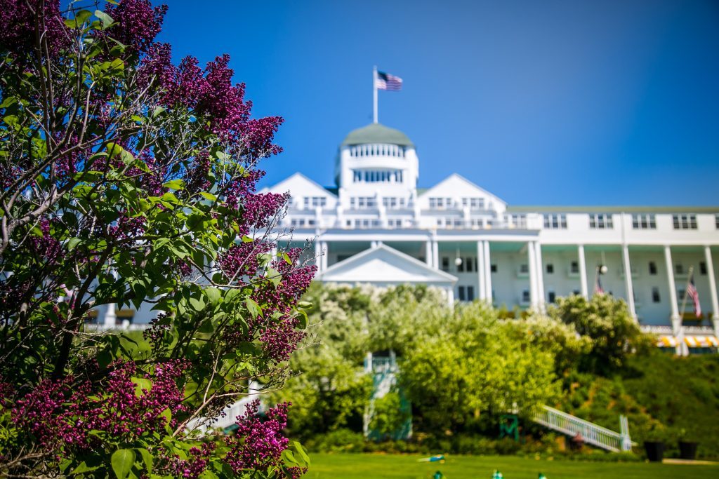Lilacs bloom in front of Mackinac Island's Grand Hotel on a sunny spring day with bright blue skies