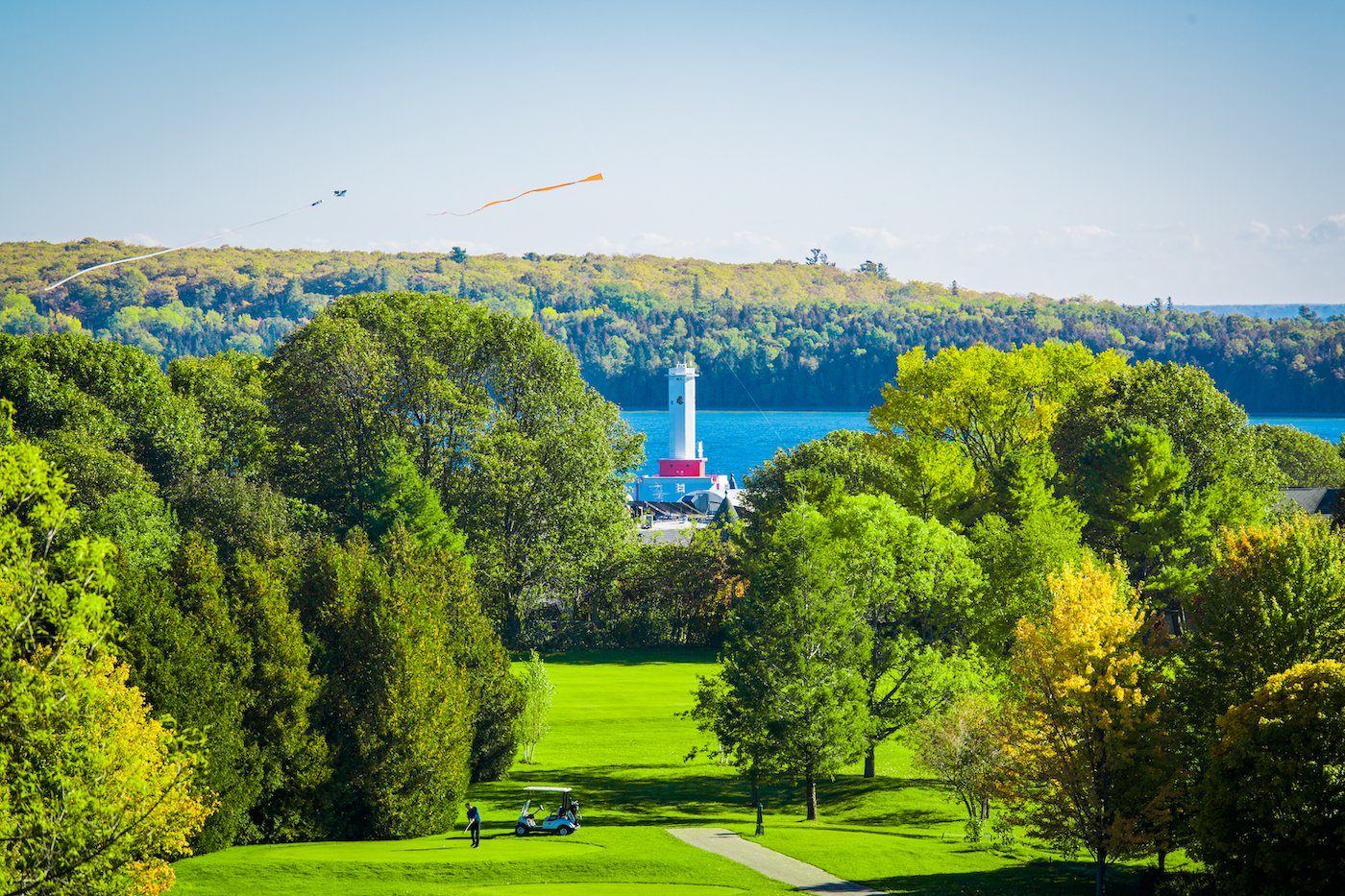 Round Island Lighthouse rises out of the water behind the trees on The Jewel Golf Course at Grand Hotel on Mackinac Island