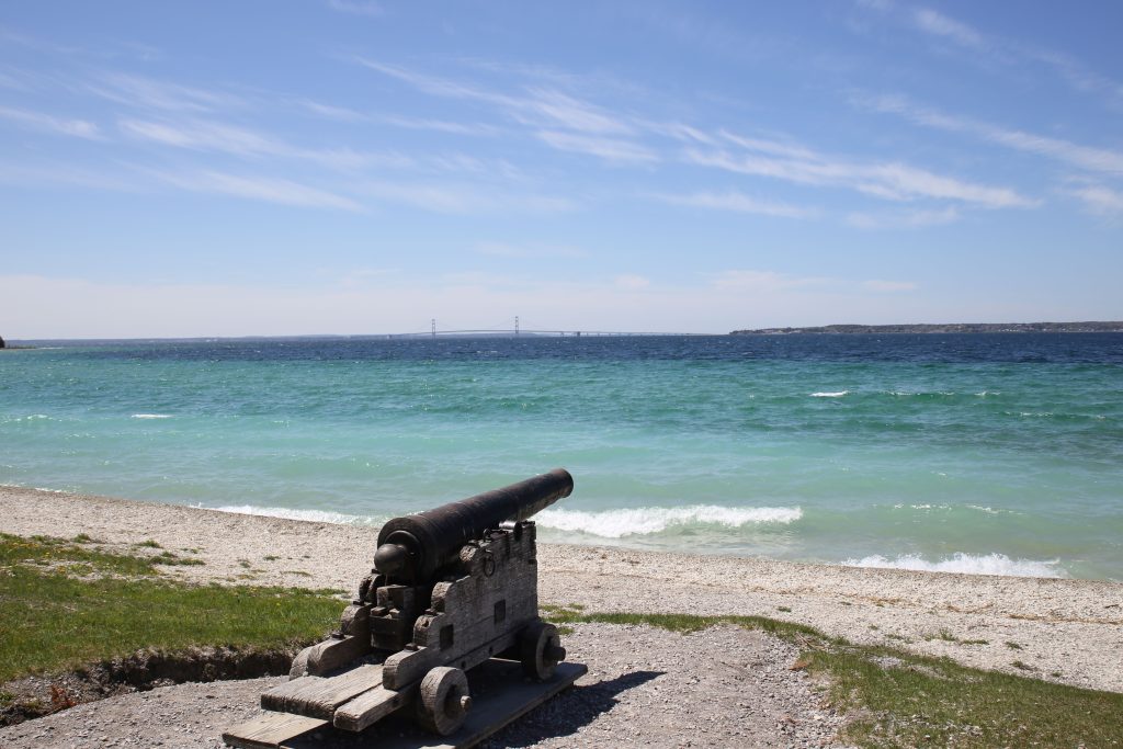 A cannon points out at the water and the Mackinac Bridge in the distance at Mackinac Island’s British Landing