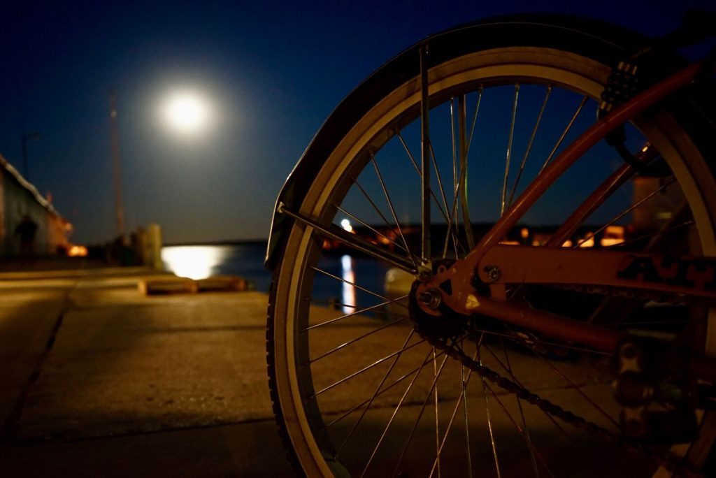 The light of a full moon shines through the spokes of a bicycle wheel on Mackinac Island