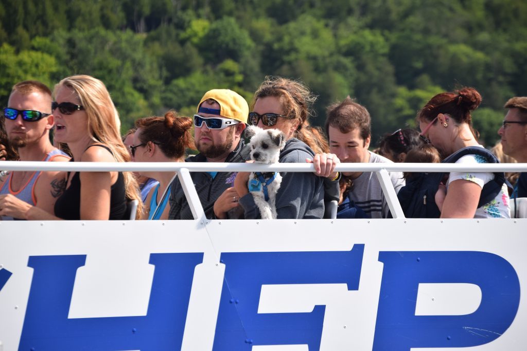 A dog rides among a group of people on a ferry boat to Mackinac Island