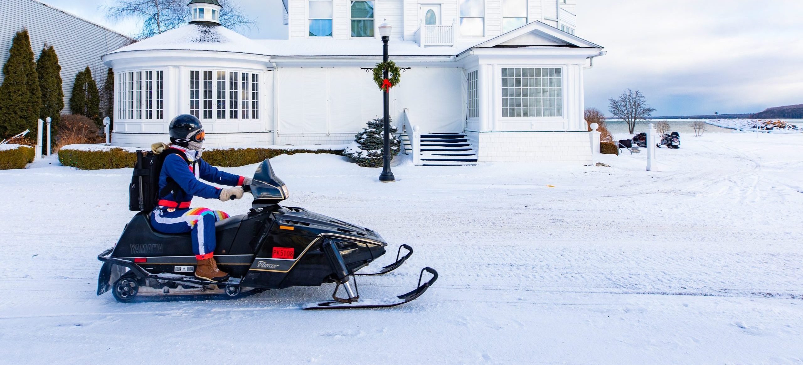 A person rides a snowmobile past a waterfront building on Michigan’s Mackinac Island