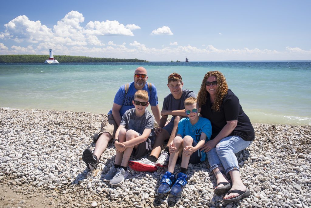 A family poses for a photo while seated on the rocky beach at Mackinac Island’s Windermere Point.