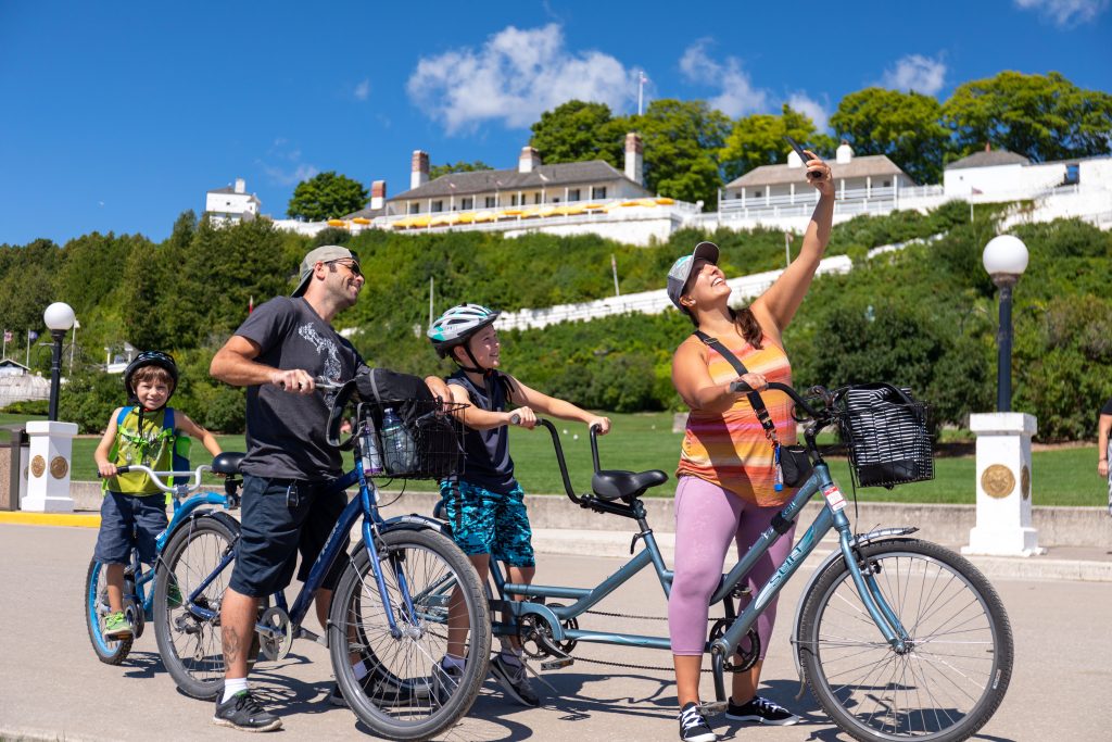 A mother snaps a selfie of her and her family while riding bicycles near Fort Mackinac on Mackinac Island