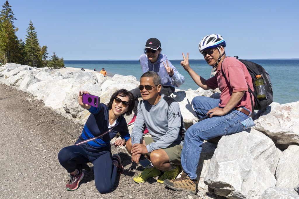 A group of four Mackinac Island visitors takes a break from riding bicycles to snap a selfie along the waterfront