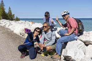 A group of four Mackinac Island visitors takes a break from riding bicycles to snap a selfie along the waterfront