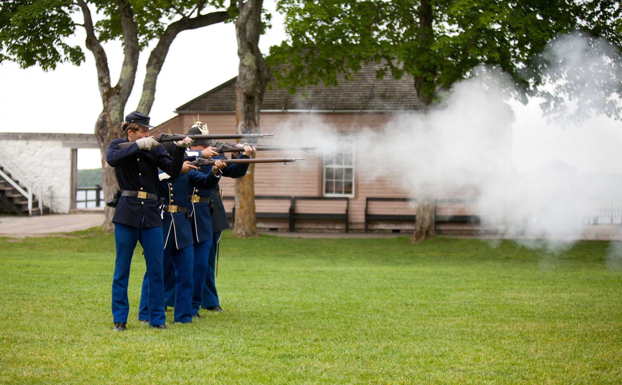 A group of costumed interpreters fires rifles at Mackinac Island’s historic Fort Mackinac
