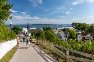 Mackinac Island visitors walk back down into town from Fort Mackinac with houses and the water in the background