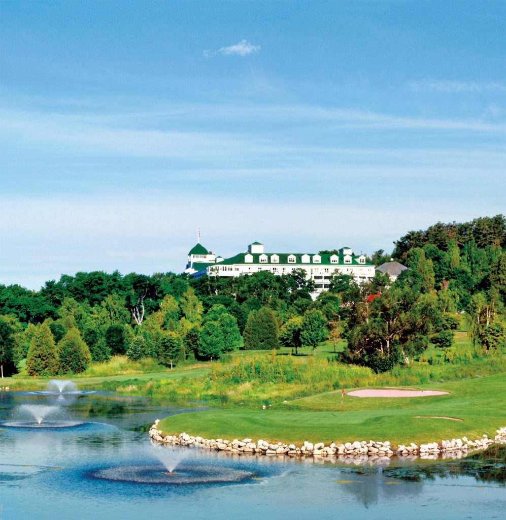 Grand Hotel looms above a green surrounded by water on The Jewel Golf Course on Mackinac Island