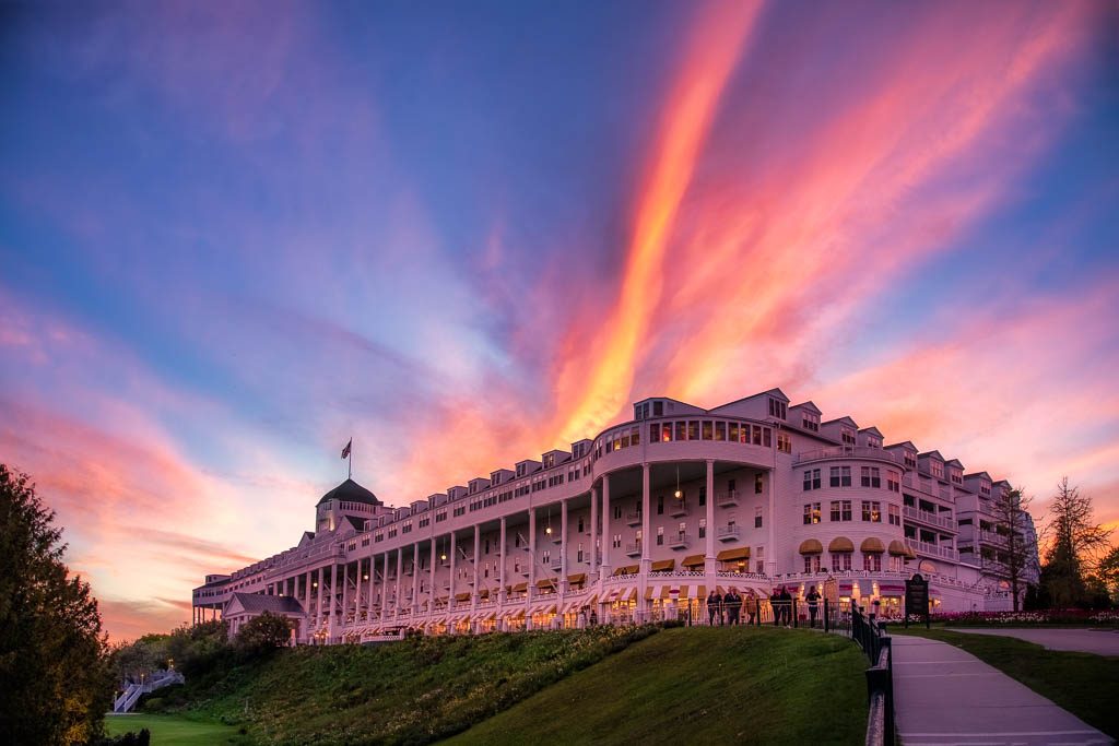 The colors of a Mackinac Island sunset streak through the sky behind and above Grand Hotel