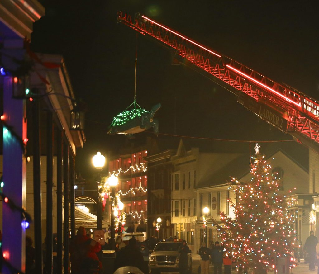 A lighted turtle drops from the sky above the Christmas tree on Mackinac Island's Main Street as a crowd gathers on New Year's Eve