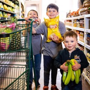 The three sons of the fourth-generation owner of Doud’s Market on Mackinac Island shop one of the store aisles.