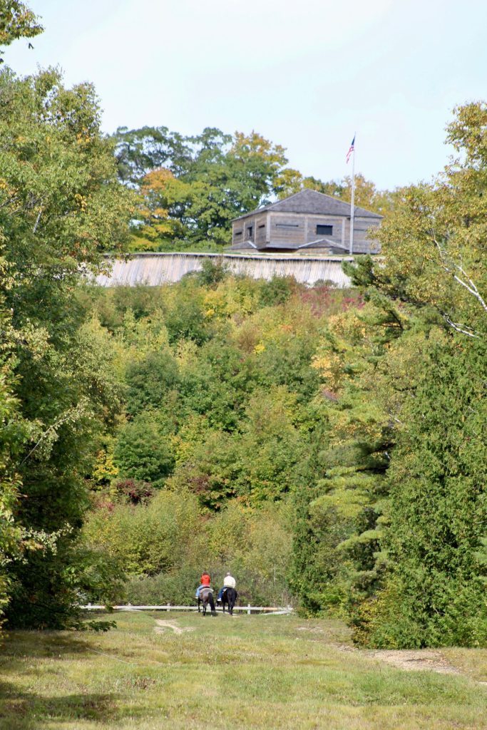 Two visitors ride horseback below Fort Holmes on the highest point on Mackinac Island