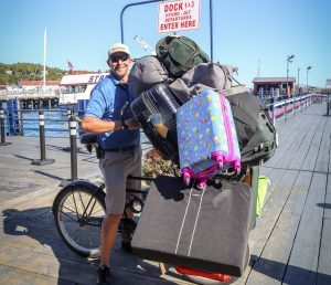 A Mackinac Island dock porter prepares to leave the ferry dock on a bicycle loaded down with several suitcases