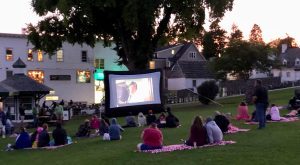 Families seated on blankets watch a movie on a big screen in Mackinac Island's Marquette Park outside Fort Mackinac
