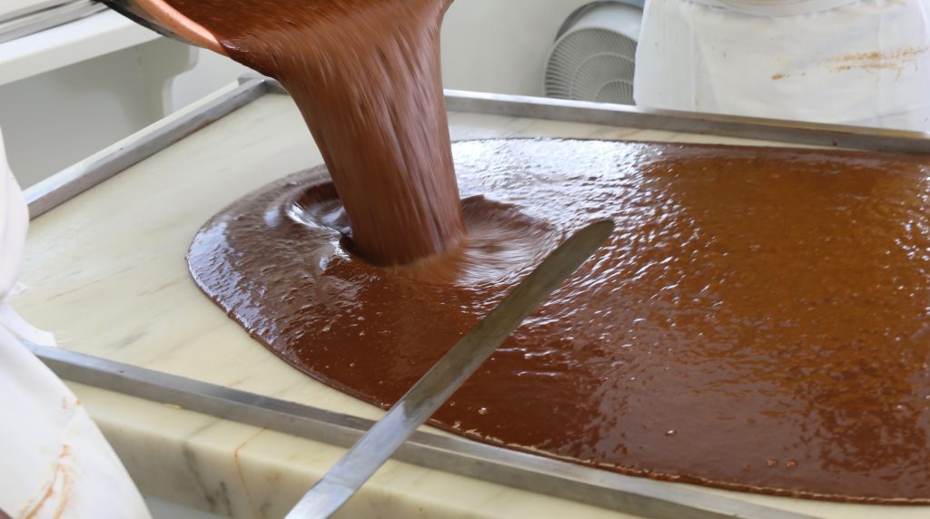 A Mackinac Island fudgemaker pours a pot full of gooey chocolate onto a marble slab where it will cool and harden.
