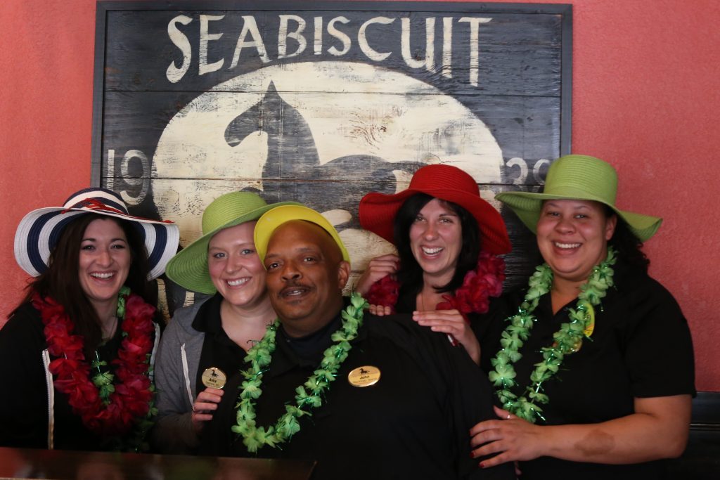 Four women wearing leis pose for a photo with a worker at Mackinac Island's Seabiscuit restaurant