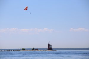 A parasailer flies high above the water and Round Island Lighthouse off Mackinac Island