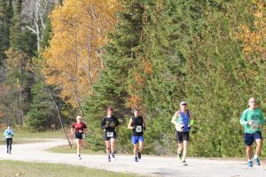 A group of runners passes by trees with gorgeous fall colors during Mackinac Island's annual Great Turtle Trail Run