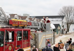 Santa Claus rides through downtown Mackinac Island on the back of a fire truck during the annual Christmas Bazaar Weekend