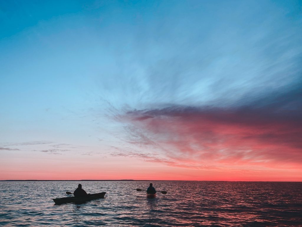 Two single kayakers paddle around Mackinac Island on a sunrise trip with Great Turtle Kayak Tours.