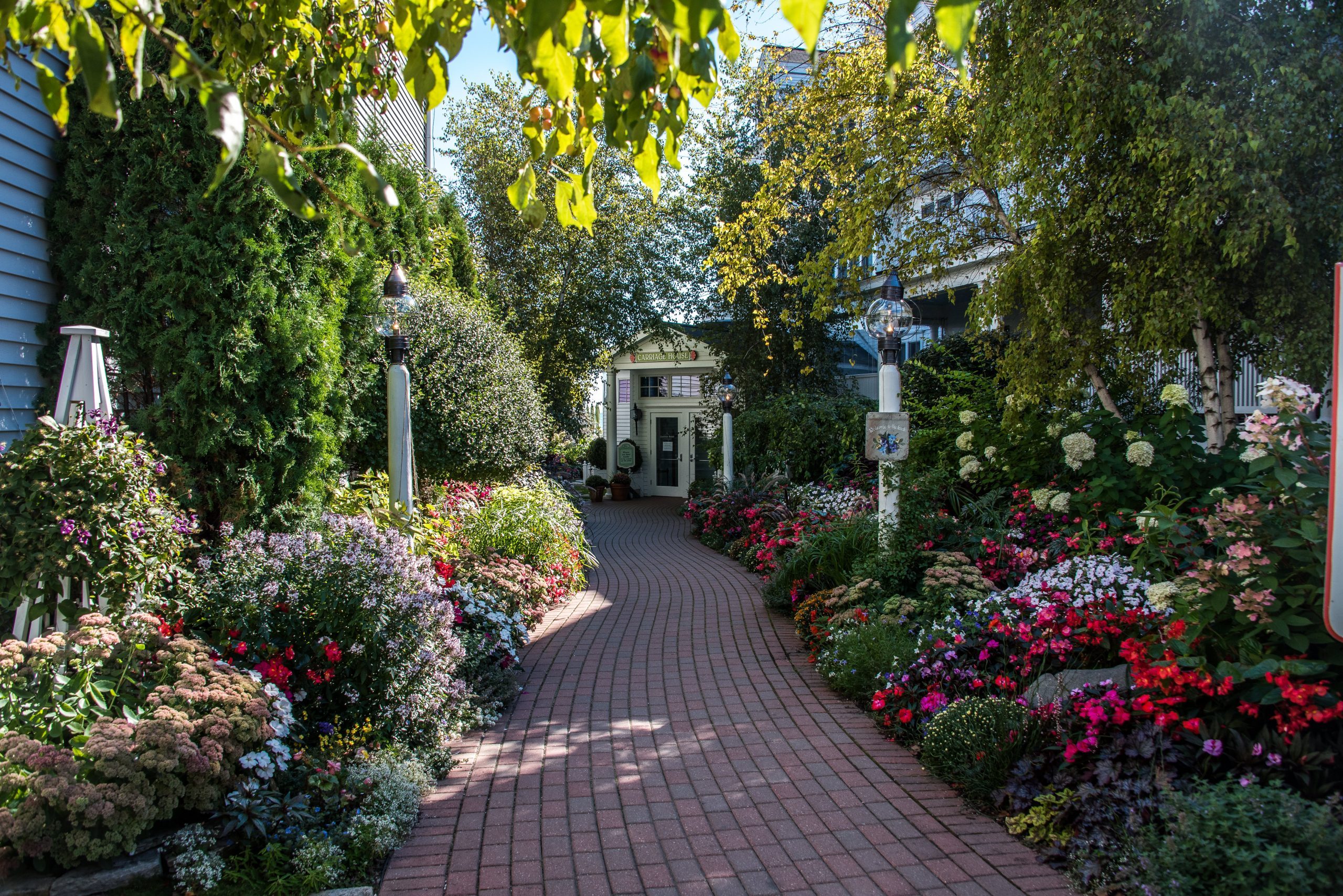 Colorful flowers line a brick paver pathway in the garden at Mackinac Island’s Hotel Iroquois.