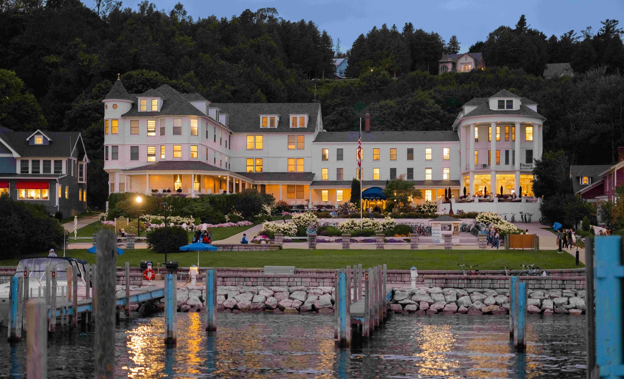 The lights of Island House Hotel reflect on the water in the Mackinac Island marina at twilight