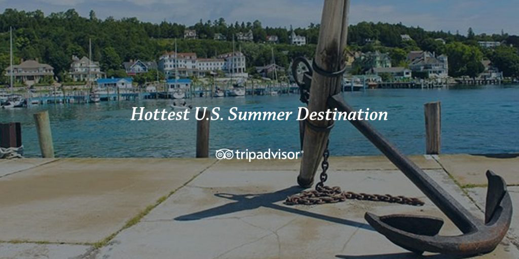 An image of a boat anchor sitting on a dock in the Mackinac Island harbor with the words "Hottest U.S. Summer Destination - TripAdvisor" over top