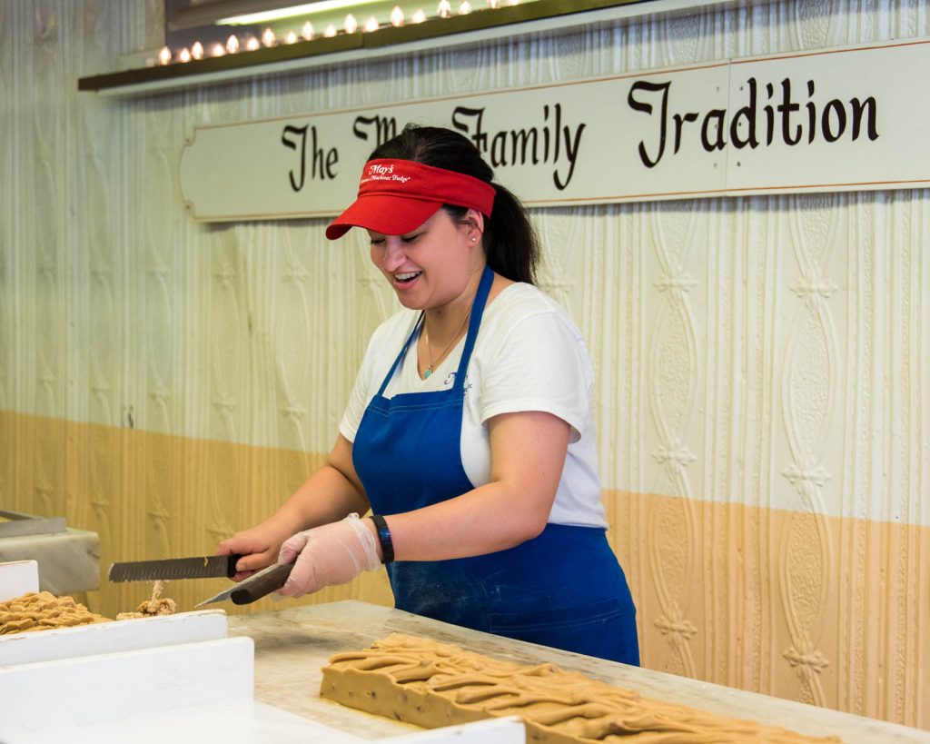 A Mackinac Island fudgemaker cuts a loaf of fudge into slices