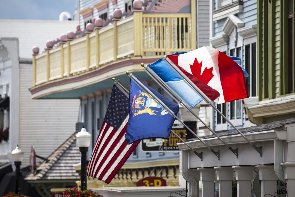 A Canadian flag flaps in the breeze on Mackinac Island’s Main Street alongside city, Michigan and American flags