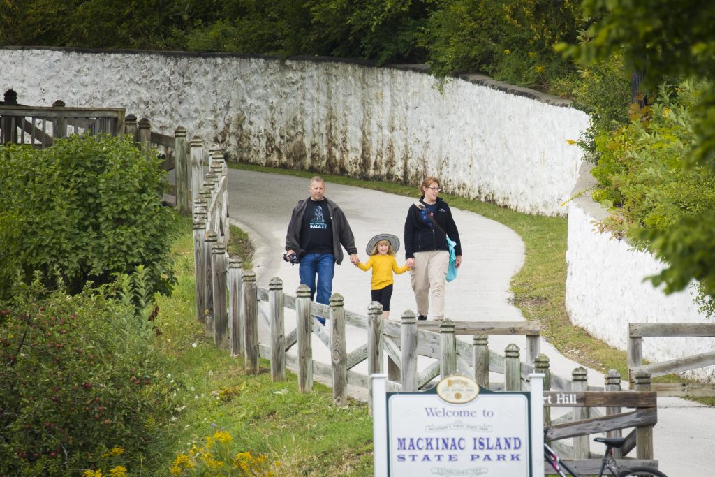 A child and two adults walk down a path in Mackinac Island State Park