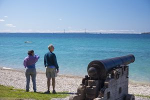 A couple admires the view from Mackinac Island’s British Landing while standing next to a beachfront cannon.