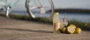 A bottle of Mackinac Island Bicycle Basket Lemonade on a boardwalk with bicycle in background
