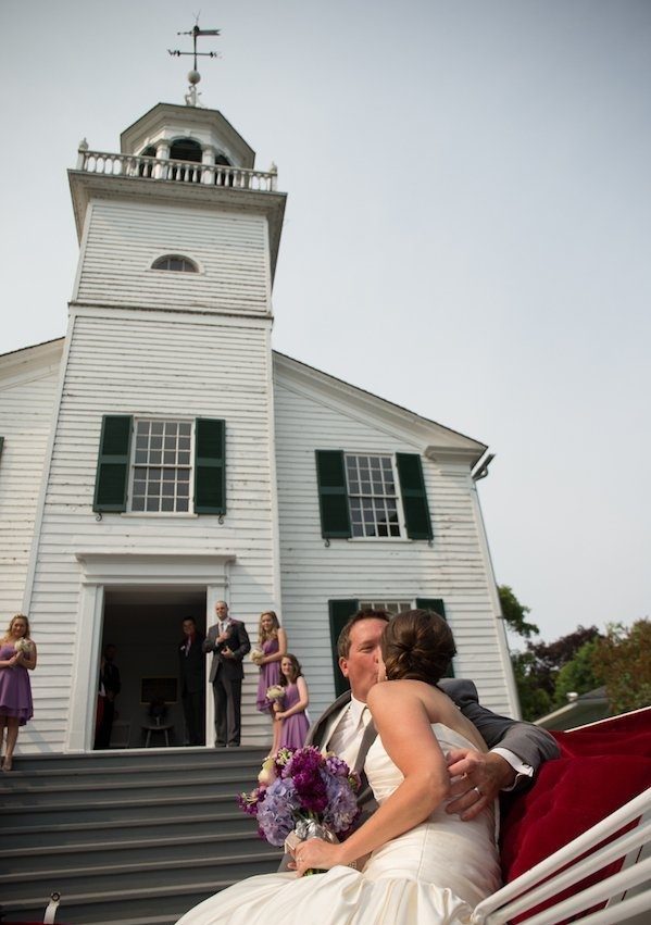 A bride and groom kiss outside historic Mission Church on Michigan's Mackinac Island