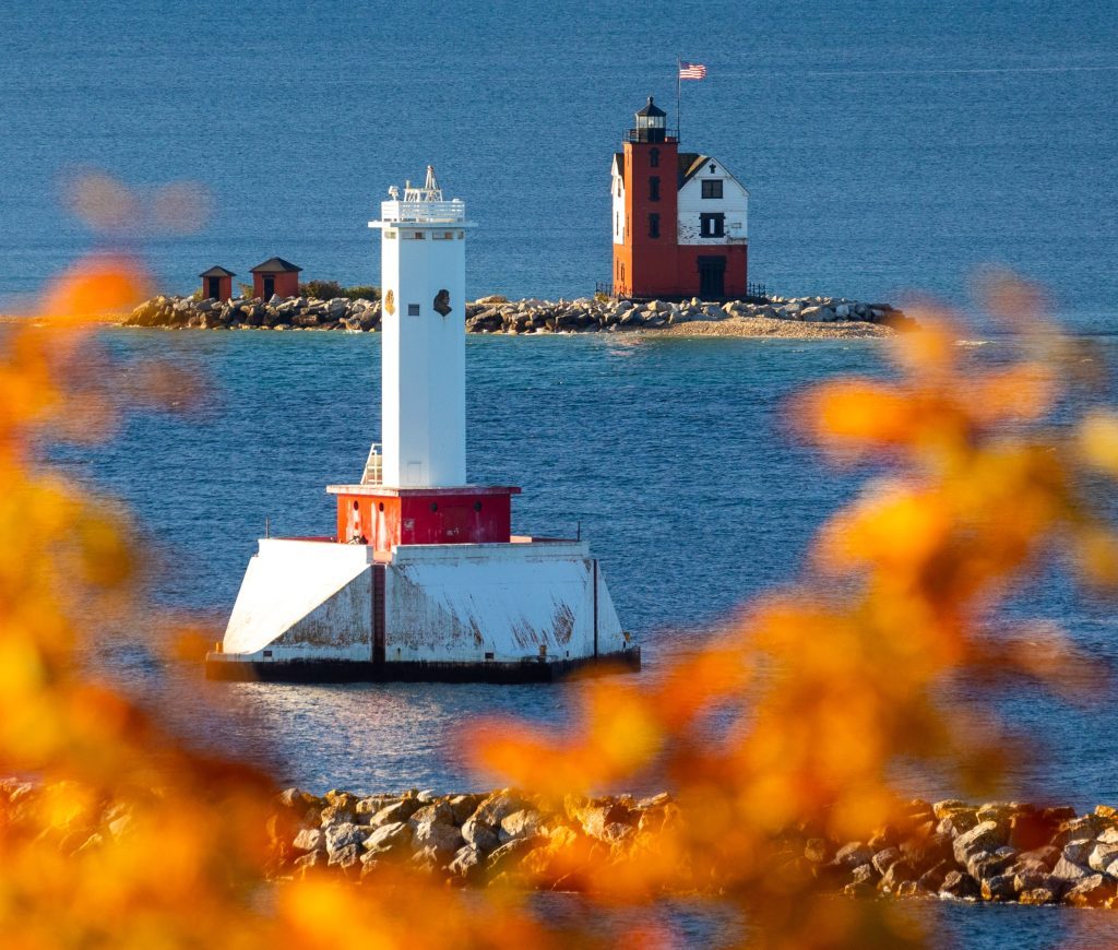 Lighthouses in the water off Mackinac Island framed by leaves in fall color