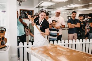 The Michigan Sugar Queen uses a wooden paddle to spread molten fudge on a marble slab as a crowd watches on Mackinac Island