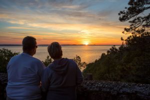 A couple looks out from Mackinac Island’s Sunset Rock at the setting sun over the water