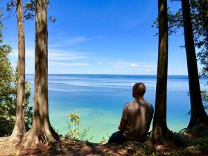 Man Sitting by Tree Enjoying View of Waters Surrounding Mackinac 