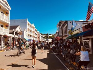 A young woman with a backpack walks amid bicycles on Main Street in downtown Mackinac Island on a sunny clear day