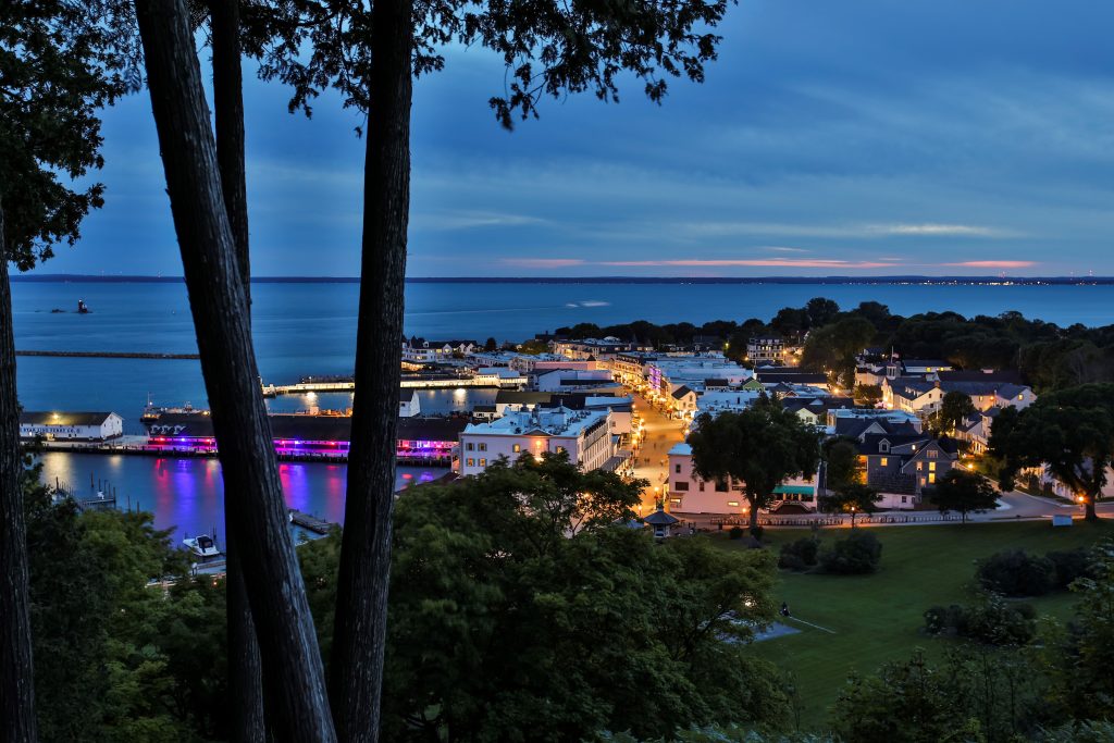 A view of downtown Mackinac Island at night with lights aglow, as seen from Anne’s Tablet above Fort Mackinac