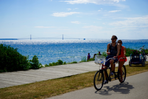 Couple Biking by Lake – Mackinac Island Tourism Bureau 