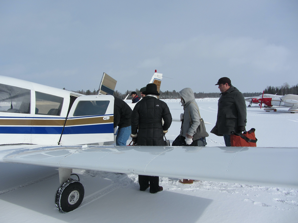 Passengers board an airplane at Mackinac Island Airport on a snowy winter day.