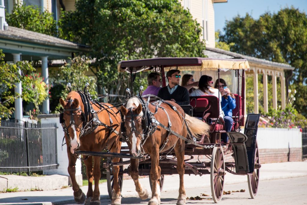 A horse-drawn carriage tours Mackinac Island on a sunny day 