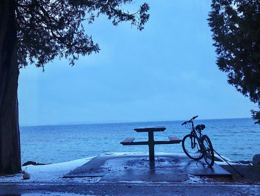 Bike and Picnic Table Surrounded by Snow and Water