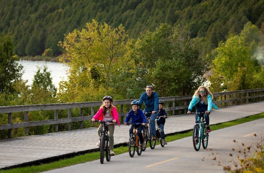 A happy family rides bikes along Mackinac Island’s M-185 highway that runs around the perimeter of the island.