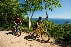 Two fat tire bikers ride along Mackinac Island’s Tranquill Bluff Trail on a guided tour.